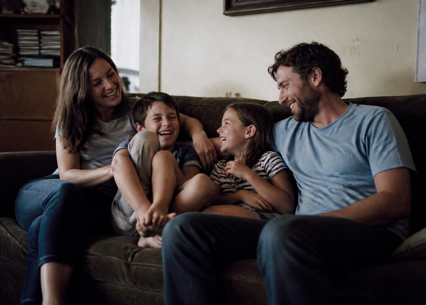 A family laughing together on the couch at home